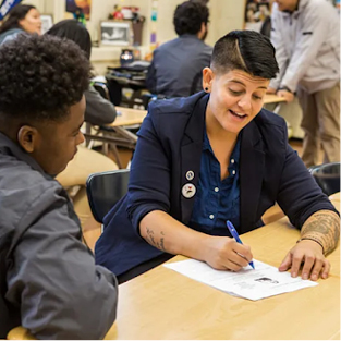 Image of a teacher and student sitting together and writing
